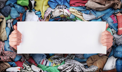 Sale concept. Hands holding a white plate on the background of a vortex of clothing