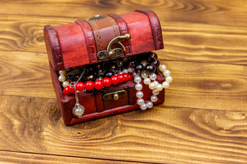 Vintage treasure chest full of jewelry and accessories on wooden background