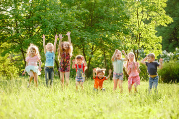 Obraz premium a group of children playing and running in the park on a green gozon.