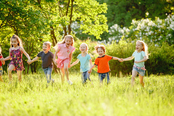 a group of children playing and running in the park on a green gozon.