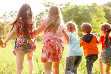 a group of children playing and running in the park on a green gozon.