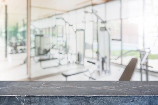 Empty black marble stone table top on blurred with bokeh Exercise room,fitnees and gym interior background - can be used for display or montage your products