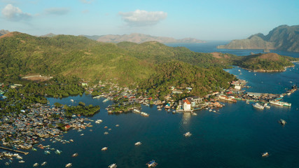 Aerial view Coron city with slums and poor district. sea port, pier, cityscape Coron town with boats on Busuanga island, Philippines, Palawan. Seascape with mountains.