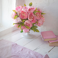 bouquet of orchids, peonies, roses in a ceramic vase and a stack of books