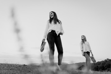 Two girls walking in the meadow, monochrome image. Copy space for text