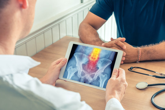 Doctor holding a digital tablet with x-ray of hips of the patient. Pain on the spine