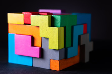 Cube made of multicolored wooden geometric shapes.