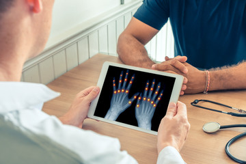 Doctor holding a digital tablet with x-ray of hands of the patient. Pain on the joints of the...