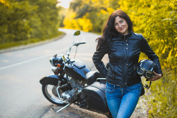 Fototapeta na wymiar attractive brunette motorcyclist standing near a motorcycle. adventure concept