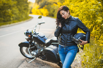 Naklejka na ściany i meble attractive brunette motorcyclist standing near a motorcycle. adventure concept