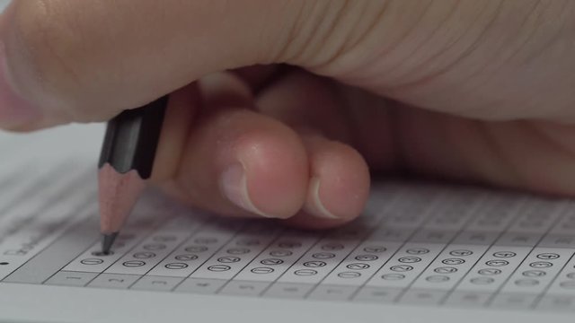 Student hand filling out in answer sheet with standardized test form
