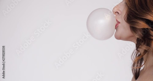 Side View Of Young Woman Blowing Pink Bubble Gum On Orange