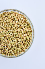 Green buckwheat untreated in a glass bowl for a healthy lifestyle on a white background.
