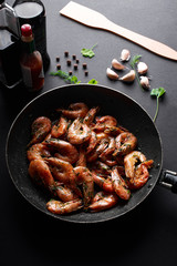 жареные креветки в сковороде на черном фоне