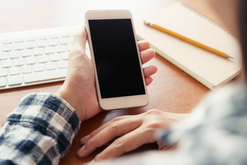 Close up hand using smartphone on desk background in office.  On hand holding smartphone blank display.