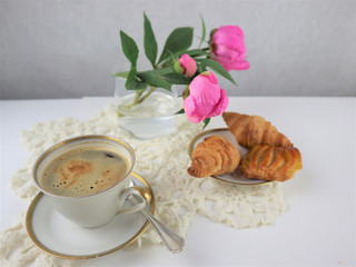 breakfast with cup of coffee and croissants, bouquet of pink flowers