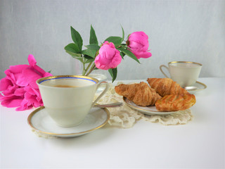 breakfast with two cups of coffee and croissants, bouquet of pink flowers