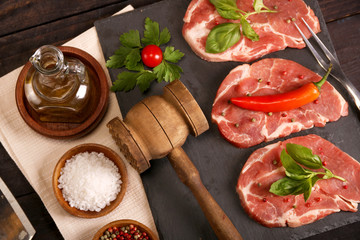 Raw pork meat steak with vegetables, salt, rosemary and spices cooking over stone table. Top view.