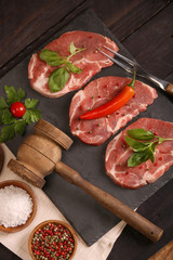Raw pork meat steak with vegetables, salt, rosemary and spices cooking over stone table. Top view.