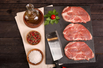 Raw pork meat steak with vegetables, salt, rosemary and spices cooking over stone table. Top view.