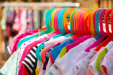 Rack of baby and children used dress, clothes displayed at outdoor hanger market for sale.
