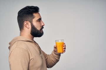 Fototapeta premium Bearded man holding a glass of orange juice