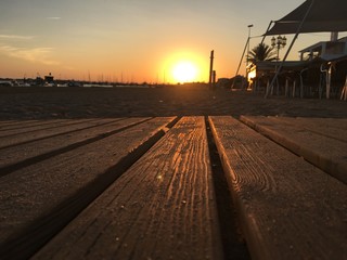 The sun setting and its reflection on the wooden walkway to the beach