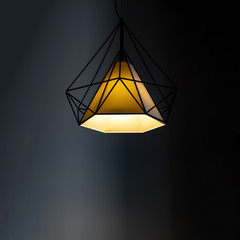 Modern lamp hanging down from ceiling in the dark background.