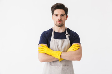 Photo of joyful young man wearing yellow rubber gloves for hands protection smiling at camera while cleaning house