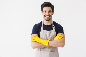 Photo of happy young man wearing yellow rubber gloves for hands protection smiling at camera while...