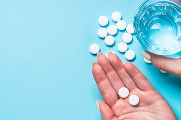Woman takes pills on blue top view.