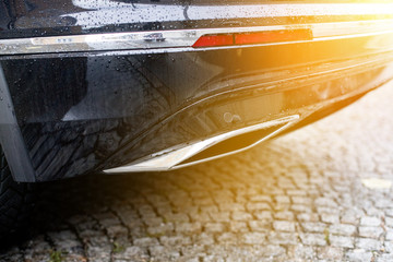 Powerful car with exhaust pipe, pollution and fine dust. Sunlight.