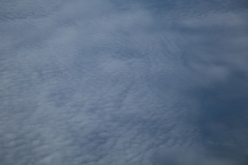 Aerial view from plane window with blue sky and white clouds
