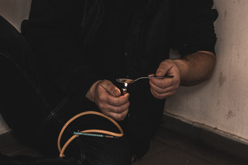 Young man addict with a syringe and heroin in the dirty basement (stairs). Drug addict. social issue