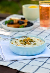 Sweet rice porridge, pudding, with raisins and pumpkin seeds in a blue bowl on the table. Delicious country breakfast.