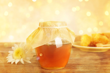 Jar with sweet honey on table against color background