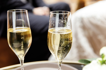 Two glasses of champagne next to a bouquet of flowers