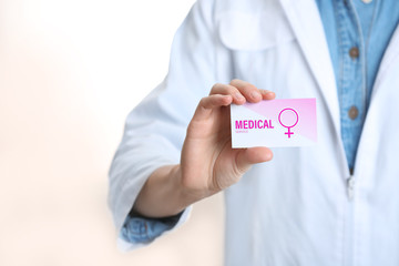 Doctor holding medical business card isolated on white, closeup. Women's health service