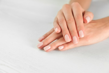 Fototapeta premium Closeup view of woman with smooth hands and manicure at table, space for text. Spa treatment