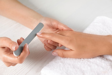 Obraz na płótnie Canvas Manicurist filing client's nails at table, closeup. Spa treatment