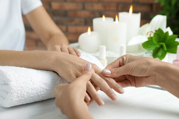 Fototapeta na wymiar Cosmetologist massaging client's hand at table in spa salon, closeup