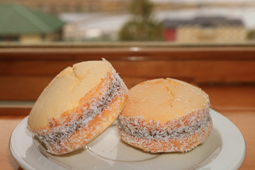 Pair of Alfajores, Traditional Latin American Filling Cookies on Wooden Table by the Window