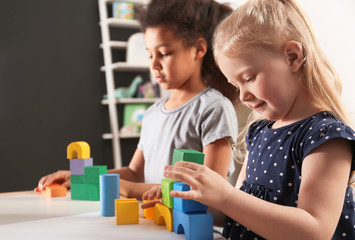 Obraz na płótnie Canvas Cute little children playing with building blocks in kindergarten. Indoor activity