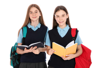 Portrait of teenage girls in school uniform with backpacks and books on white background