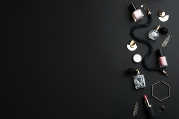Composition with perfume bottles, cosmetics and jewellery on black background, flat lay. Space for text