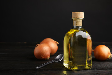 Glass bottle of onion syrup and fresh vegetable on dark background. Space for text