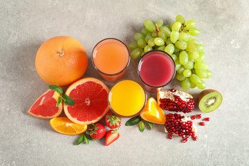 Glasses of different juices and fresh fruits on table, top view