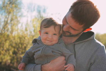 Cute baby boy on his dad's shoulders walking on road outdoors, sensitivity to nature concept