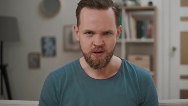 Portrait of angry man displeased and fearful doing disgust face because aversion reaction, annoyance guy sitting on a sofa at home. motional guy disgusted expression, feeling angry, indoor.