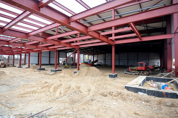 At the construction site. View of a hangar building, an excavator and dump trucks loaded